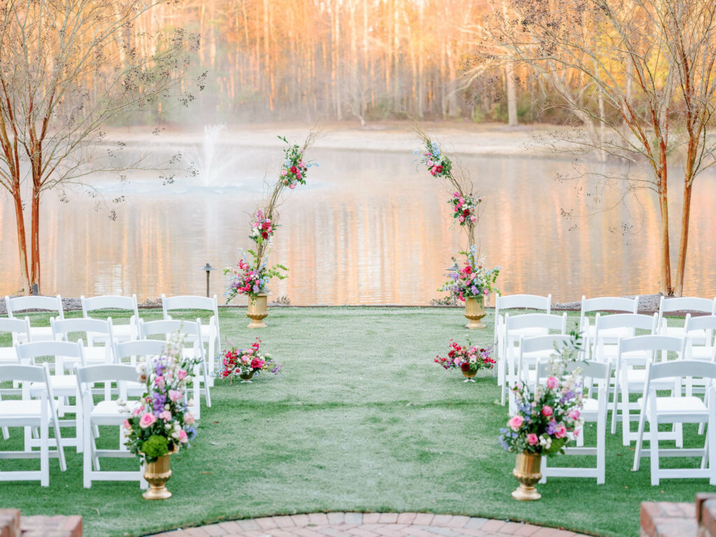 walnut hill ceremony site at pond with bright flowers down the aisle