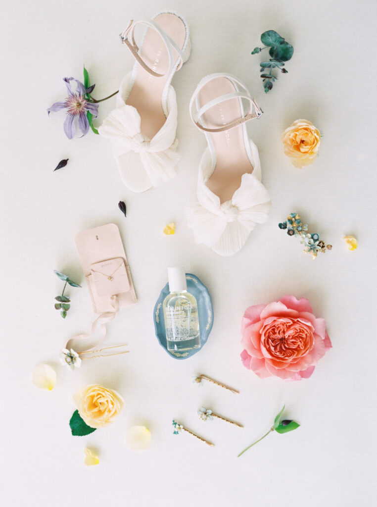 flat lay for wedding with perfume and shoes and flowers