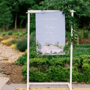 blue fabric wedding welcome sign with a watercolor barn painting