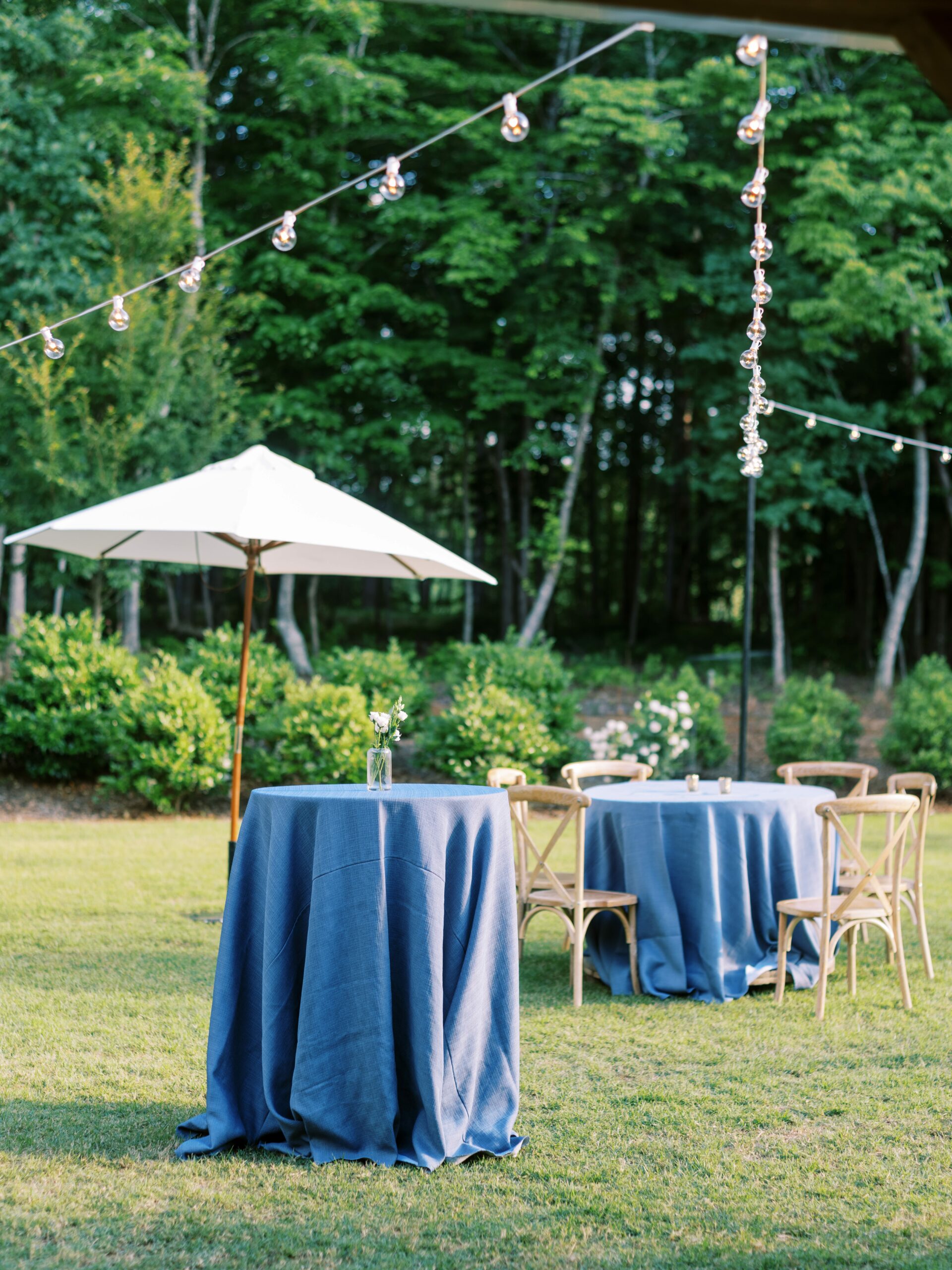 white and blue wedding barn or chapel hill cocktail hour with tables and umbrella