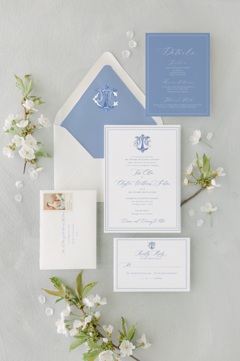 shuler studio blue and white monogram invitation on top of white envelope with blue envelope liner