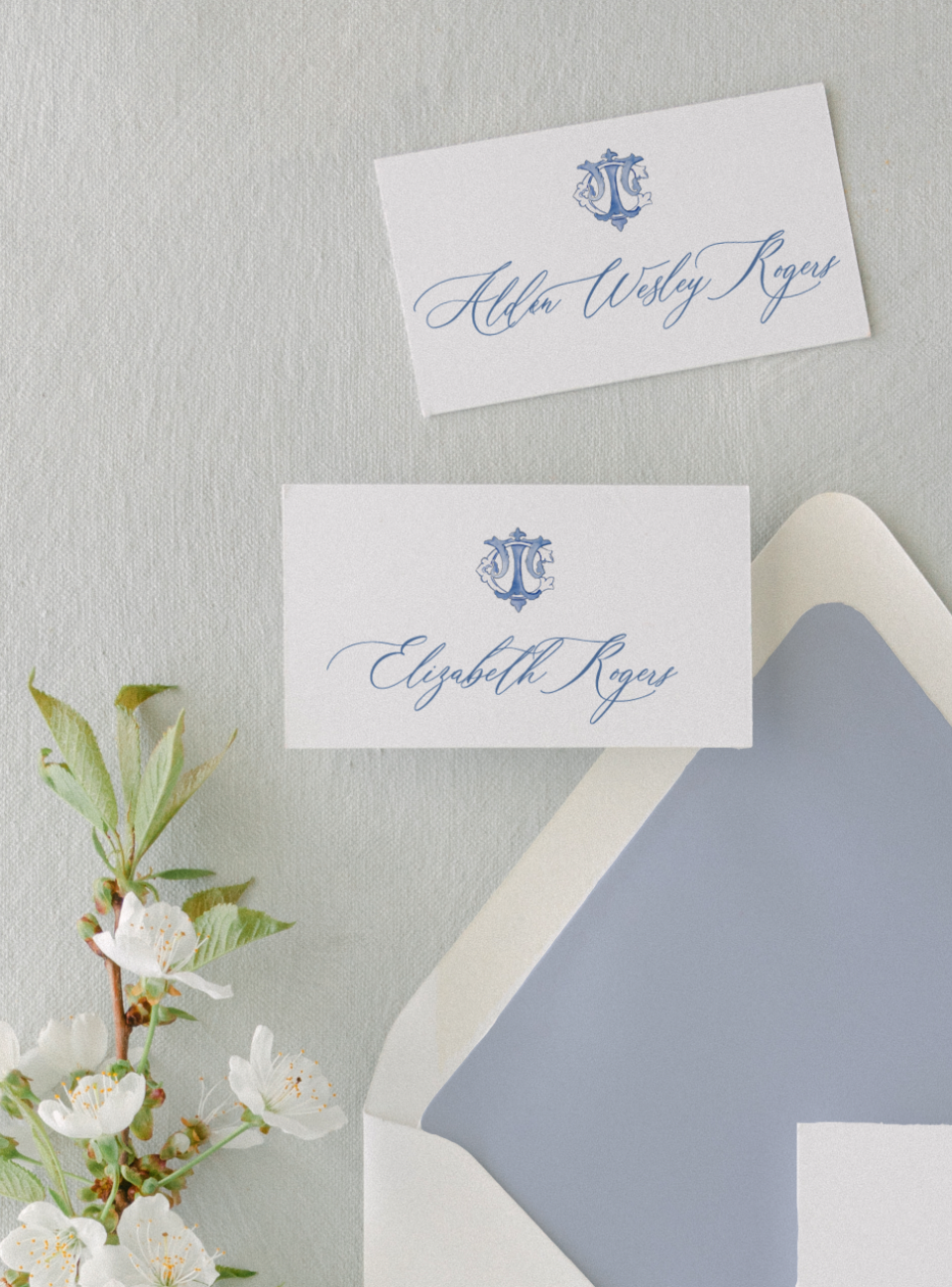 blue calligraphy wedding place cards on grey background with blue ink
