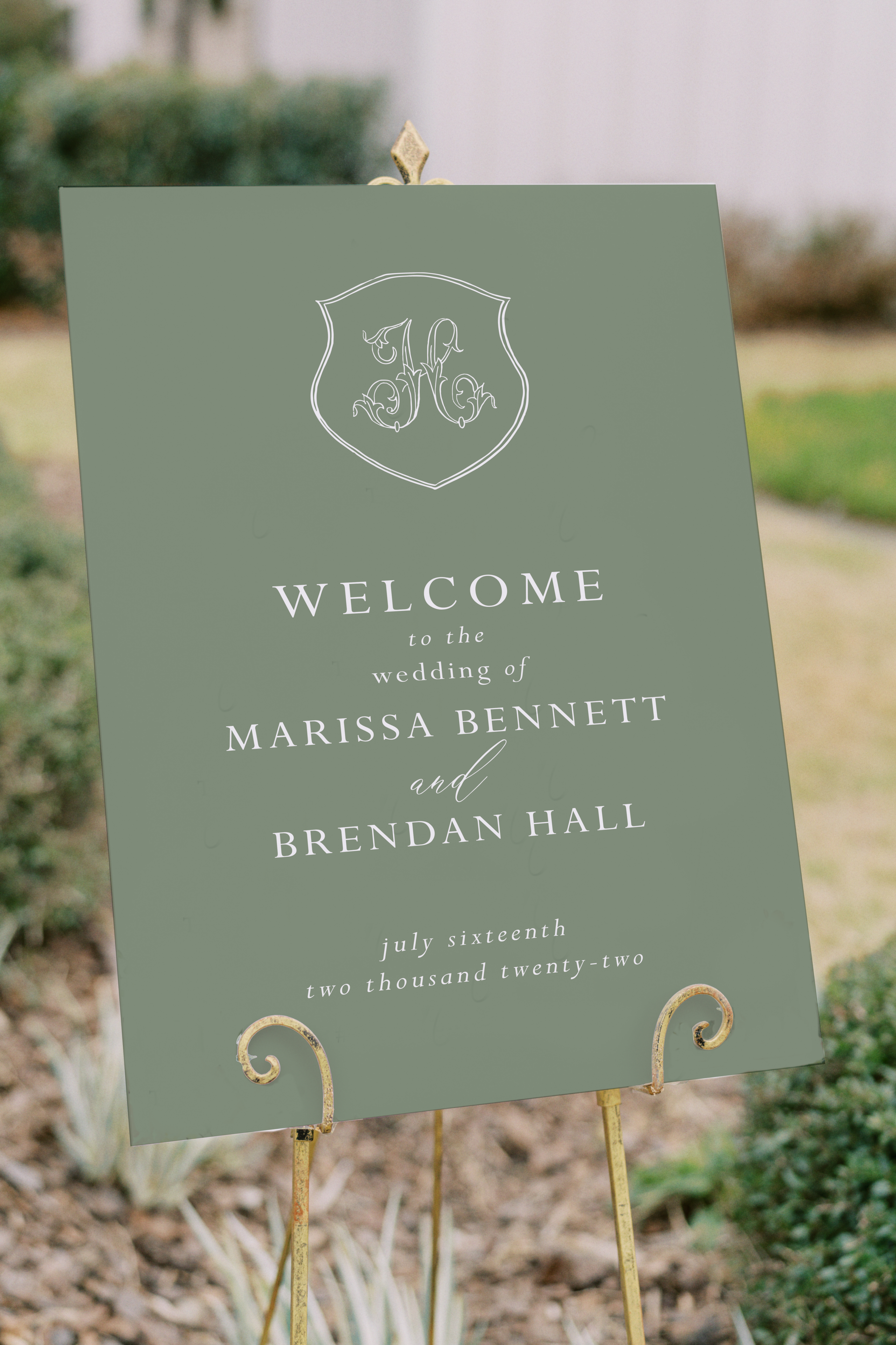 green wedding welcome sign on easel with crest