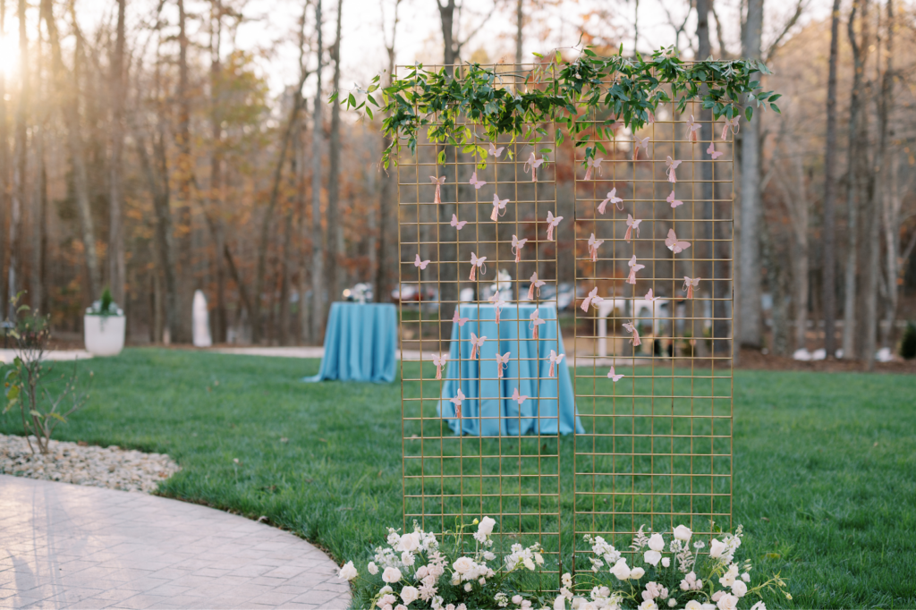 wedding cocktail hour on lawn with tables and butterfly seating chart display