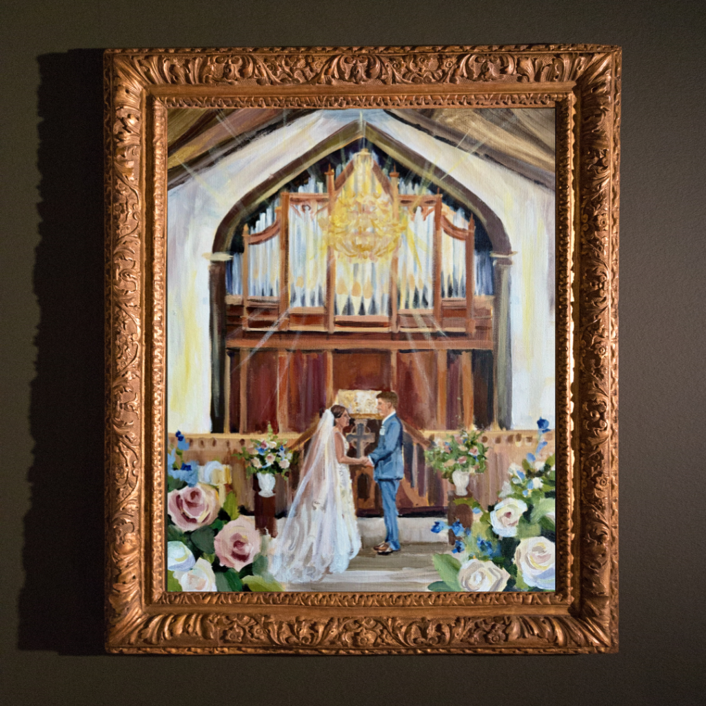 acrylic live wedding painting framed in gold depicting a vow exchange live wedding painting inside of a chapel
