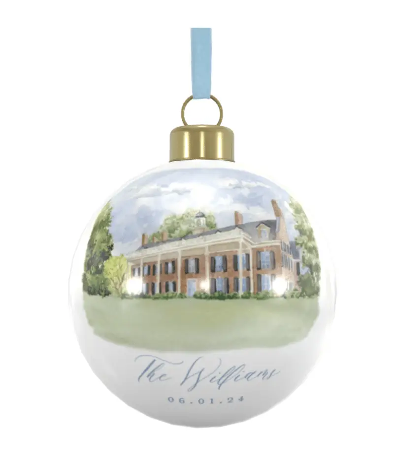 a hanging bone china Christmas ornament featuring a watercolor illustration of the Carolina inn with light blue velvet ribbon