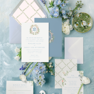 blue spring pastel garden wedding invitation on blue background with a trellis envelope liner and handpainted details amongst blue and green flowers and greenery