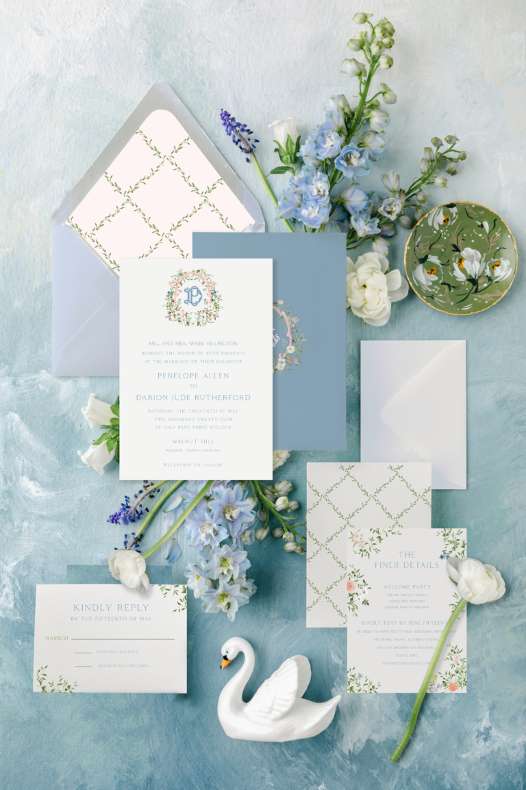 blue spring pastel garden wedding invitation on blue background with a trellis envelope liner and handpainted details amongst blue and green flowers and greenery