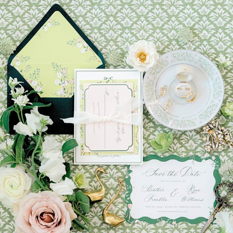 chinoiserie wedding stationery on green background with various Bridgeton inspired decorative objects