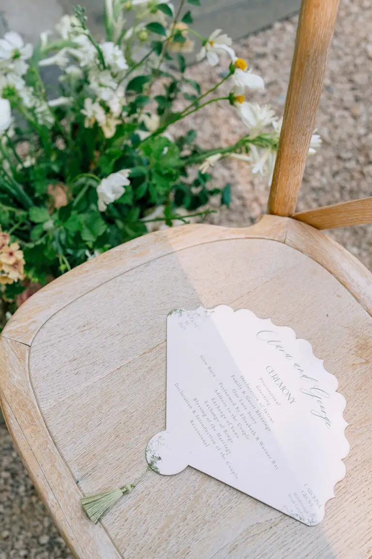 wedding fan program lying on rattan chair at Carolina grove wedding ceremony